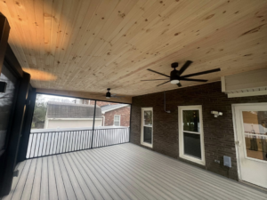 The interior of a screened-in porch featuring a wood ceiling and fans by Decks Unlimited in Littleton, CO.