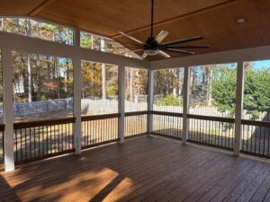 An interior view of a screened porch with a large ceiling fan and dark composite decking, built by Elite Xteriors NC in Cary, NC.