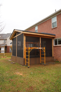 A screened porch under construction with scaffolding in the backyard, a project by Vision Construction in Framingham, MA.