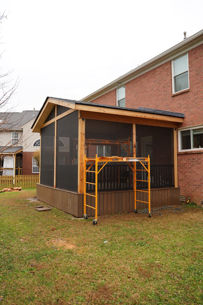 A screened porch under construction with scaffolding in the backyard, a project by Vision Construction in Framingham, MA.