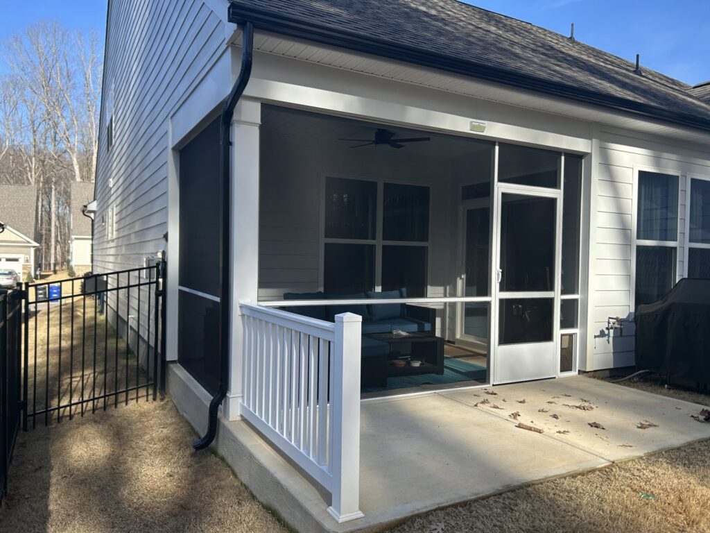 A newly installed screened porch featuring a white railing and a convenient dog door by Screen Enc in Denver, NC
