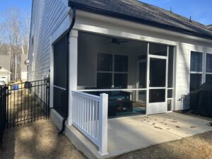 A newly installed screened porch featuring a white railing and a convenient dog door by Screen Enc in Denver, NC