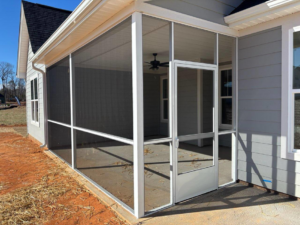 A newly built screened porch with a ceiling fan attached to a light grey house by AccampoBros Home Solutions in Greenville, SC.