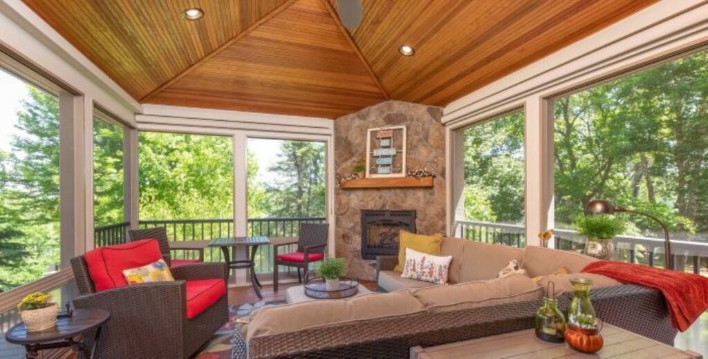 A cozy screened porch with a stone fireplace and wooden ceiling by J Brothers Design- Build- Remodel, Inc. in Corcoran, MN
