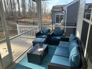 The interior of a comfortable screened porch furnished with outdoor seating, completed by Screen Enc in Denver, NC