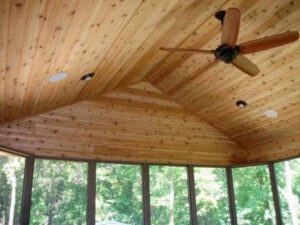 Interior view of a screened porch with a wooden plank ceiling and ceiling fan installed by Tschida Construction in Cologne, MN.