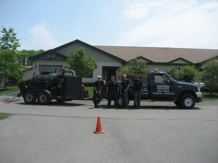 The Empire Sealcoating crew standing with their work truck and sealcoating trailer in Albany, NY