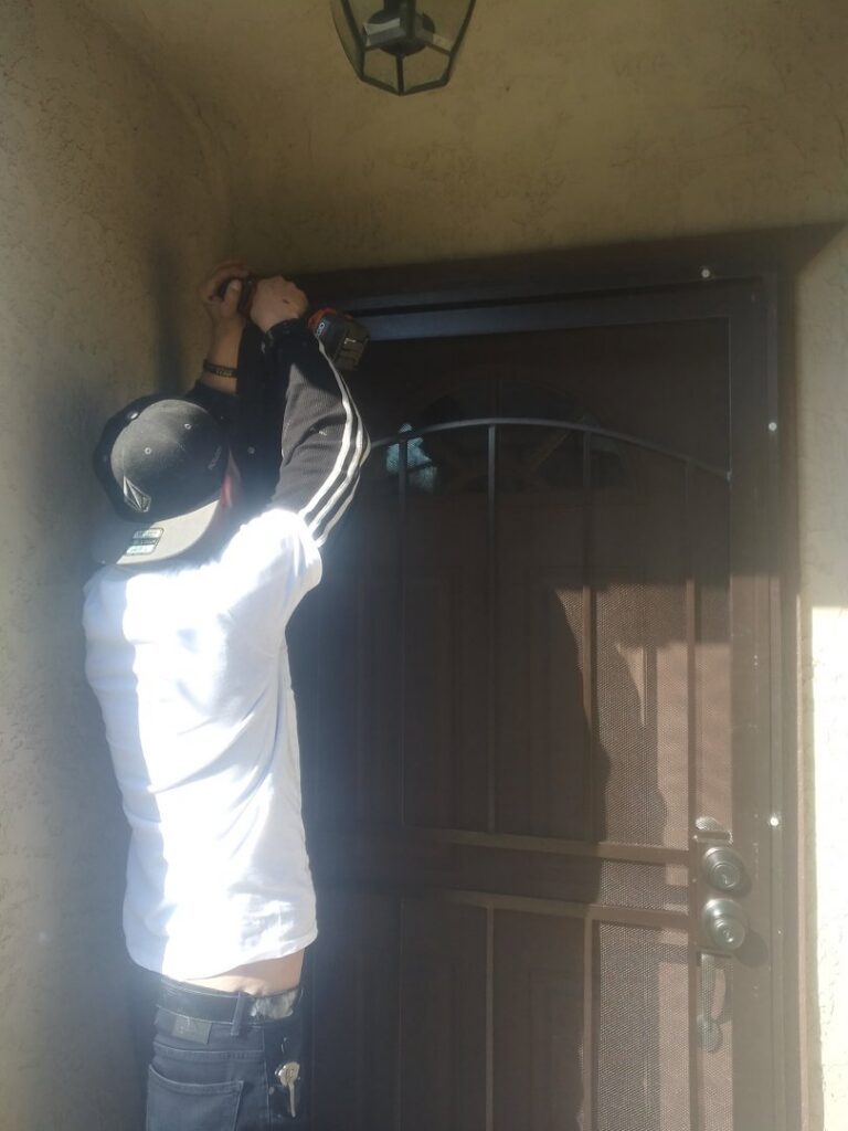 A contractor installing a new security screen door with a drill for Red Gator Maintenance in Fresno, CA.