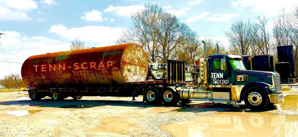 A Tenn-Scrap semi-truck hauling a large industrial tank on a flatbed trailer in Jackson, TN.
