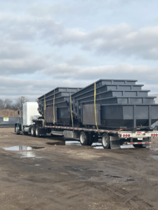 A semi-truck transporting multiple empty roll-off dumpsters for Premier Recycling and Disposal in Waukesha, WI.