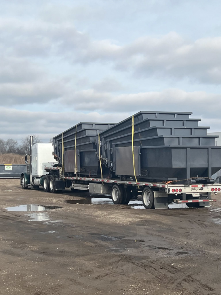 A semi-truck transporting multiple empty roll-off dumpsters for Premier Recycling and Disposal in Waukesha, WI.