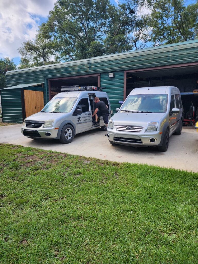 Two service vans parked outside a garage, one with Tim's Maintenance & Repair logo, in Las Vegas, NV