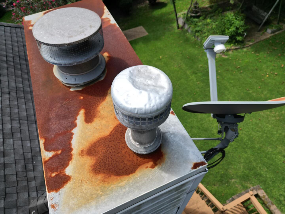A close-up view of a severely rusted metal chimney cap and vents, indicating a need for handyman repair from Hyde Roofing, LLC in Birmingham, AL