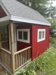 A newly built or refurbished red wooden shed with a small porch by K-Way's Handyman Services in Lincoln, NE