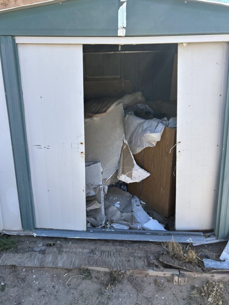 An open shed overflowing with debris and junk, indicating a cleanout service by Discount Hauling in Las Cruces, NM.