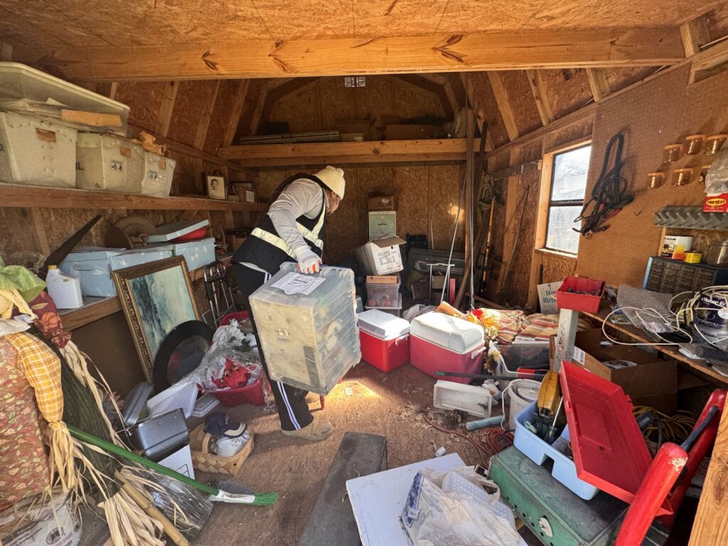 A worker performing a shed cleanout, removing various items as part of a junk removal service by City to City Junk Removal Fort Worth, TX.