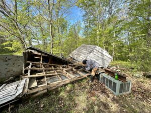 A worker dismantling a shed with debris scattered around, indicating a shed removal and junk cleanup job by Top Tier Waste Services LLC in Lancaster, OH