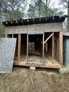 A partially demolished or repaired shed structure, showing framing and removed panels, by Ed Hauls It All in Raleigh, NC.