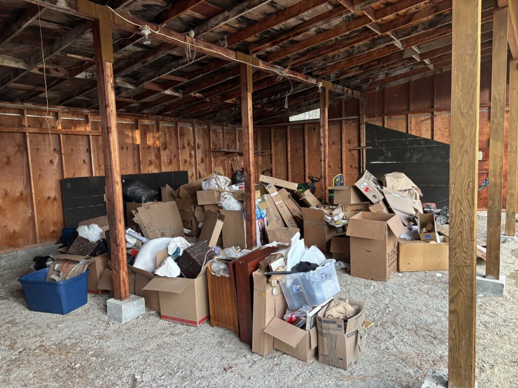 A shed or garage interior filled with a large accumulation of boxes and miscellaneous junk, ready for removal by Missoula Junk Removal, LLC in Missoula, MT.