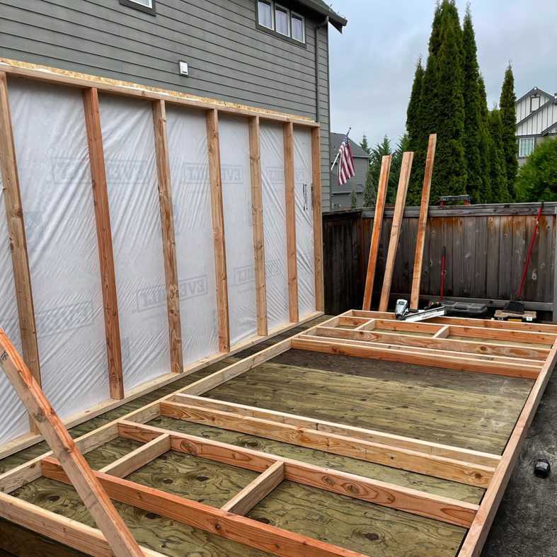 Shed framing under construction with some walls covered in a protective membrane by Shed Crafters in Sycamore, IL