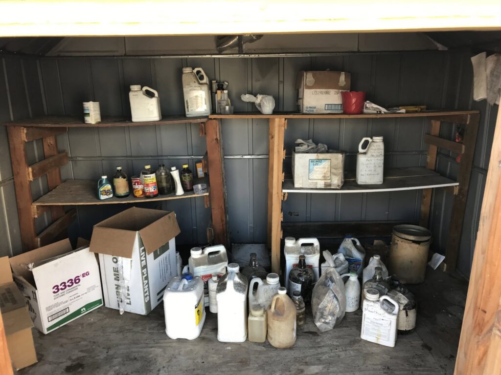 An interior view of a shed with shelves and floor filled with various hazardous materials for removal by Hazawaytoday.com in El Segundo, CA