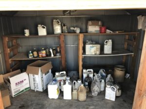 An interior view of a shed with shelves and floor filled with various hazardous materials for removal by Hazawaytoday.com in El Segundo, CA