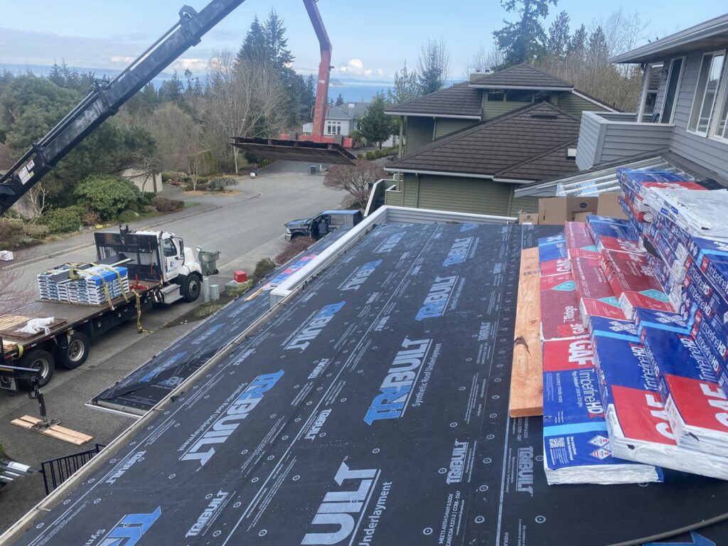 Bundles of new shingles being delivered by crane for a roof replacement by Sunny's roofing LLC in Denver, CO.