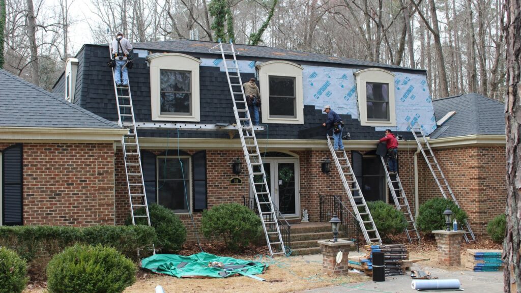 A crew installing new shingles on a residential roof, a handyman service by Consolidated Roofing Systems, Inc. in Cary, NC