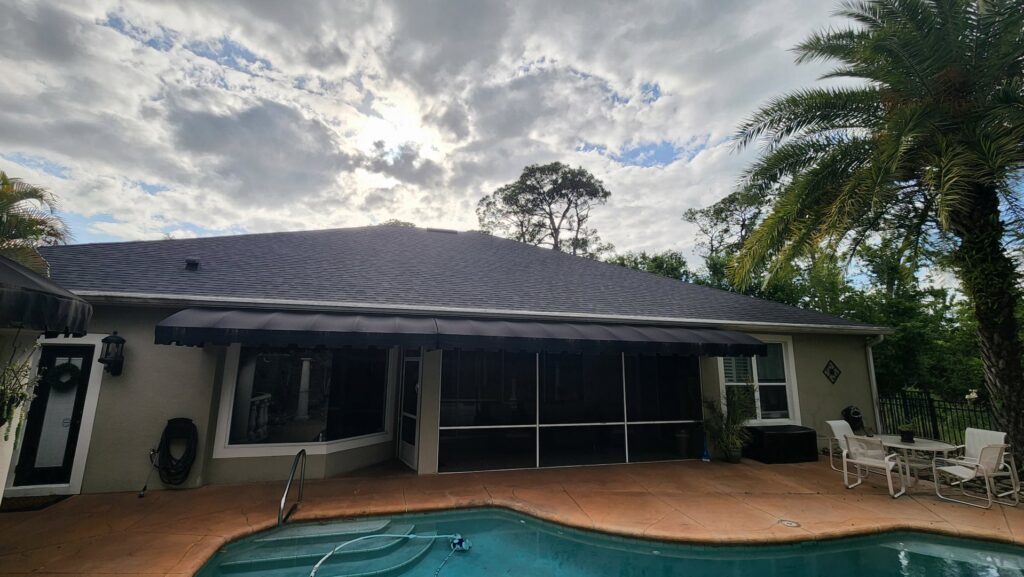 A house with a dark shingle roof and a black awning over a patio area, representing a completed project by Hastings Roofing Service Inc. in Orlando, FL.