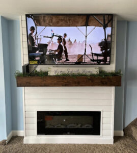 A newly installed shiplap fireplace with a mounted television and wooden mantel by Garrett Group Construction in Philadelphia, PA.