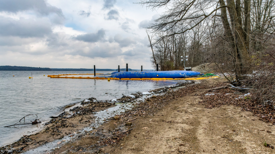 Shoreline construction with blue water barriers and yellow boom by Wilkinson Excavating, Inc. in Meadville, PA
