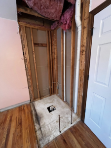 Shower area under construction with exposed studs, plumbing, and insulation by Fine Line Painting and Design in Georgetown, KY.