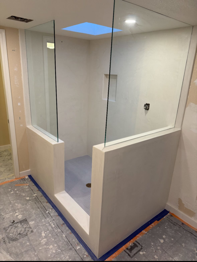 A shower area under construction with newly installed glass panels and tiled floor by Orange Door Custom Coatings in Phoenix, AZ.
