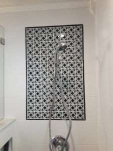 Detailed view of a shower fixture and intricate tile work in a renovated bathroom by Guaranteed Installations in Tampa, FL.