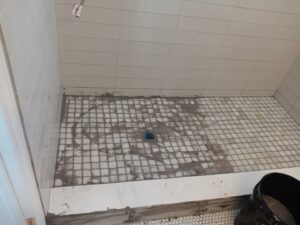 Shower floor tile installation in progress with small mosaic tiles and mortar by Juancho's Handyman in Salida, CO.