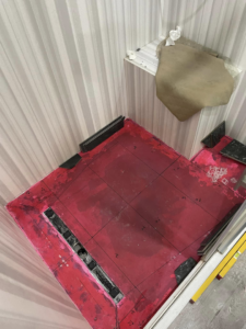 A shower floor with a red waterproofing membrane applied, ready for tiling by Form Fluent in Kodiak, AK.