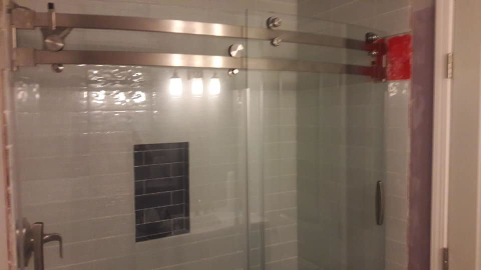A modern tiled shower with a new sliding glass door installed by Capstone Handyman in Sacramento, CA
