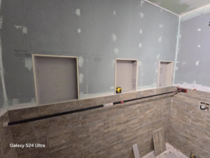 Framed shower niches and partial wall tiling during a bathroom remodel project by Torres Services in Anchorage, AK.