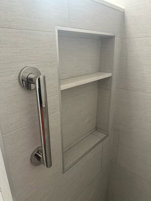 A modern shower with a built-in niche and safety grab bar installed by Dynamic Design & Remodeling in Westport, CT