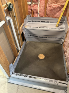 An in-progress shower pan waterproofing installation with RedGard membrane by G-P Construction in Springfield, OR.