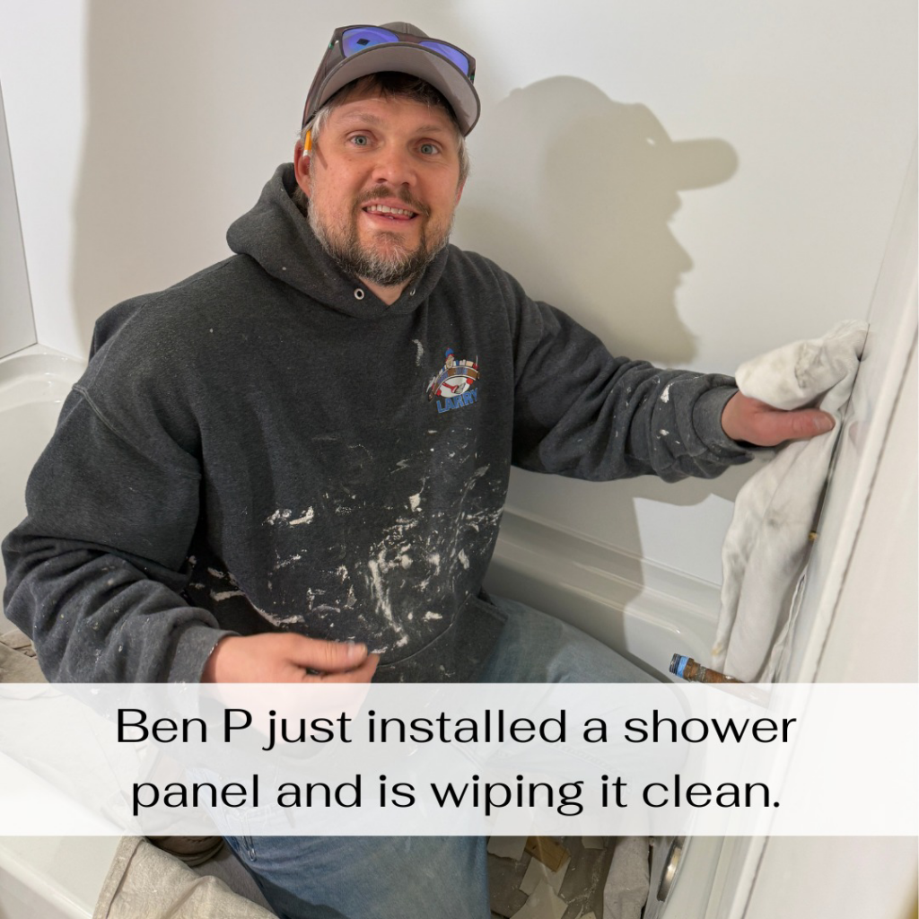 Ben P from Odd Job Larry wiping down a newly installed shower panel in a bathroom in Kenosha, WI.