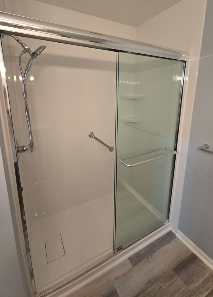 A functional shower with a sliding glass door and safety grab bar installed by The Shower Company in Kansas City, MO.