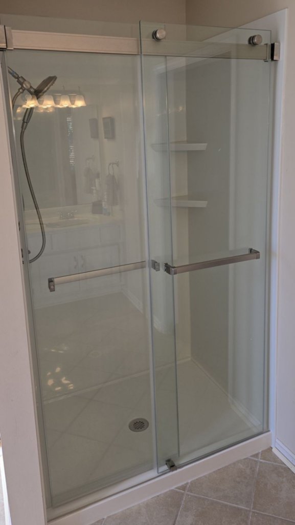 A clean shower enclosure with sliding glass doors and a bright white interior by The Shower Company in Kansas City, MO.