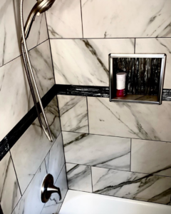 Close-up of a shower with elegant marble-look tiles and a built-in niche by Mohawk Home Improvement of Syracuse LLC in Syracuse, NY.