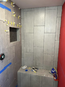 In-progress shower tile installation with large grey tiles and spacers by G-P Construction in Springfield, OR.