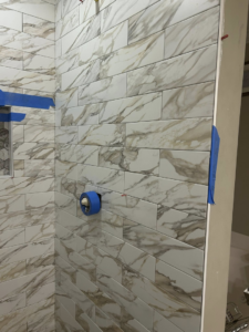 Shower tile installation in progress, showing new tiles and painter's tape by Ingram Painting and Renovation in Birmingham, AL.