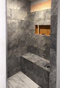 A shower stall with dark grey marble-look tiles being installed by Kizer Construction in Owensboro, KY.