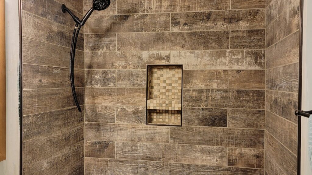 Walk-in shower with wood-look tile and a built-in niche by KC's Improvement & Construction Co., Inc. in Greensboro, NC