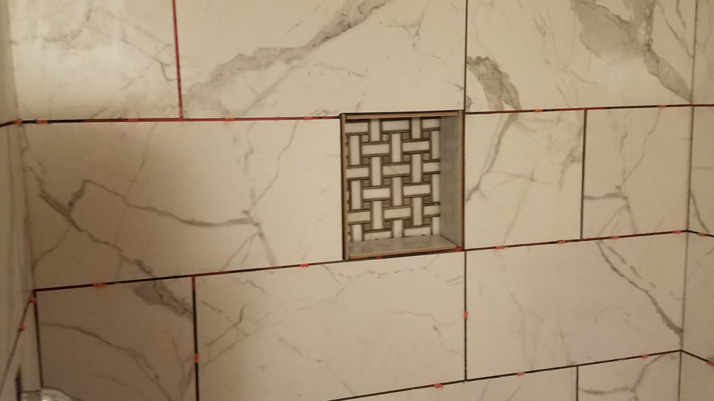 A newly tiled shower wall with a decorative niche, showcasing tile installation by Clayton's Remodeling And Home Services in Vero Beach, FL.