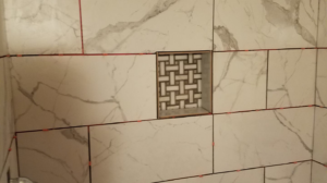 A newly tiled shower wall with a decorative niche, showcasing tile installation by Clayton's Remodeling And Home Services in Vero Beach, FL.